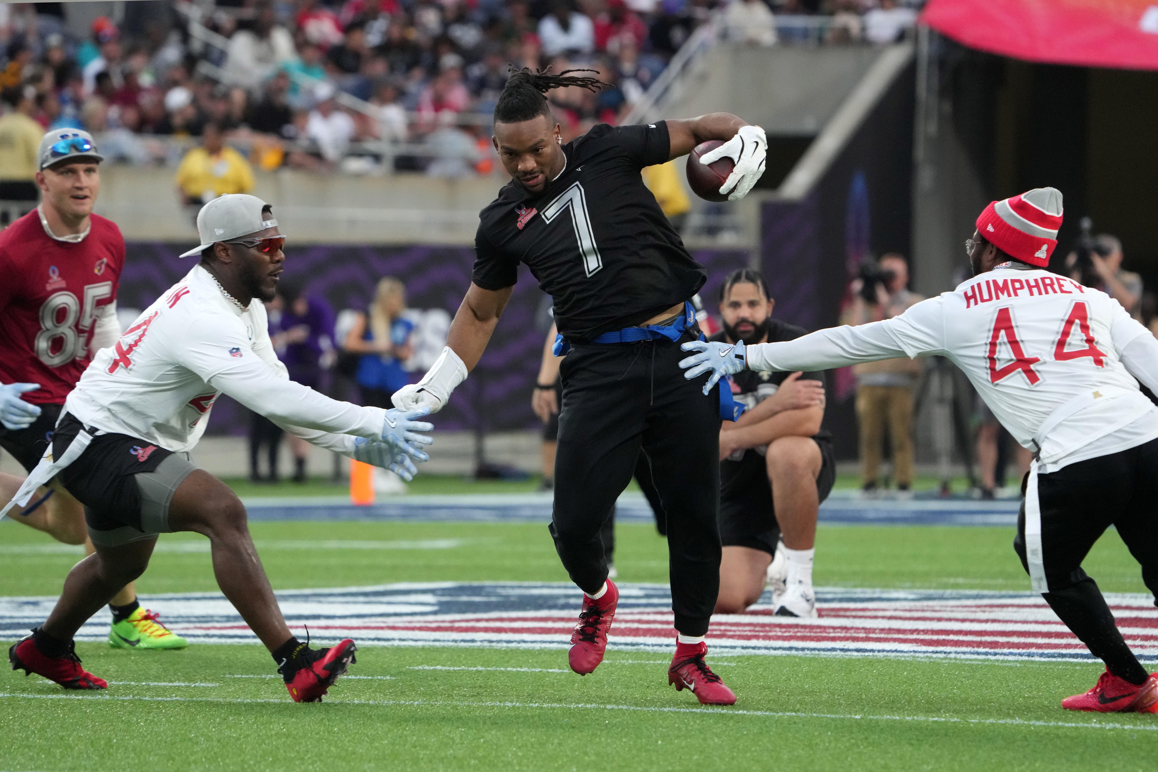 Running back Bijan Robinson of the Atlanta Falcons carries the ball against AFC linebacker Zaire Franklin of the Indianapolis Colts (left) and cornerback Marlon Humphrey of the Baltimore Ravens during the 2025 Pro Bowl Games at Camping World Stadium. — Kirby Lee