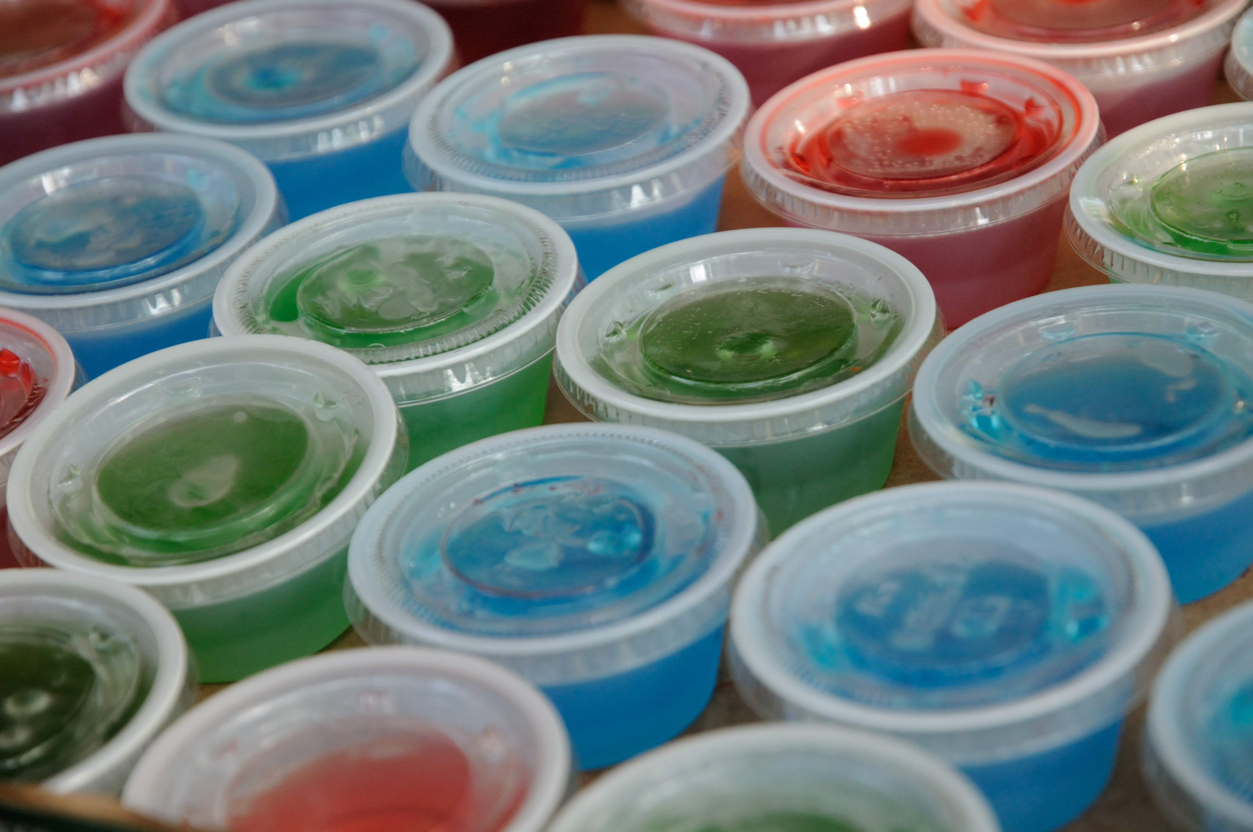Jello shots in plastic cups with lids on.  Served at parties and bars as a fun food, typically containing liquor such as vodka,tequila or whiskey.